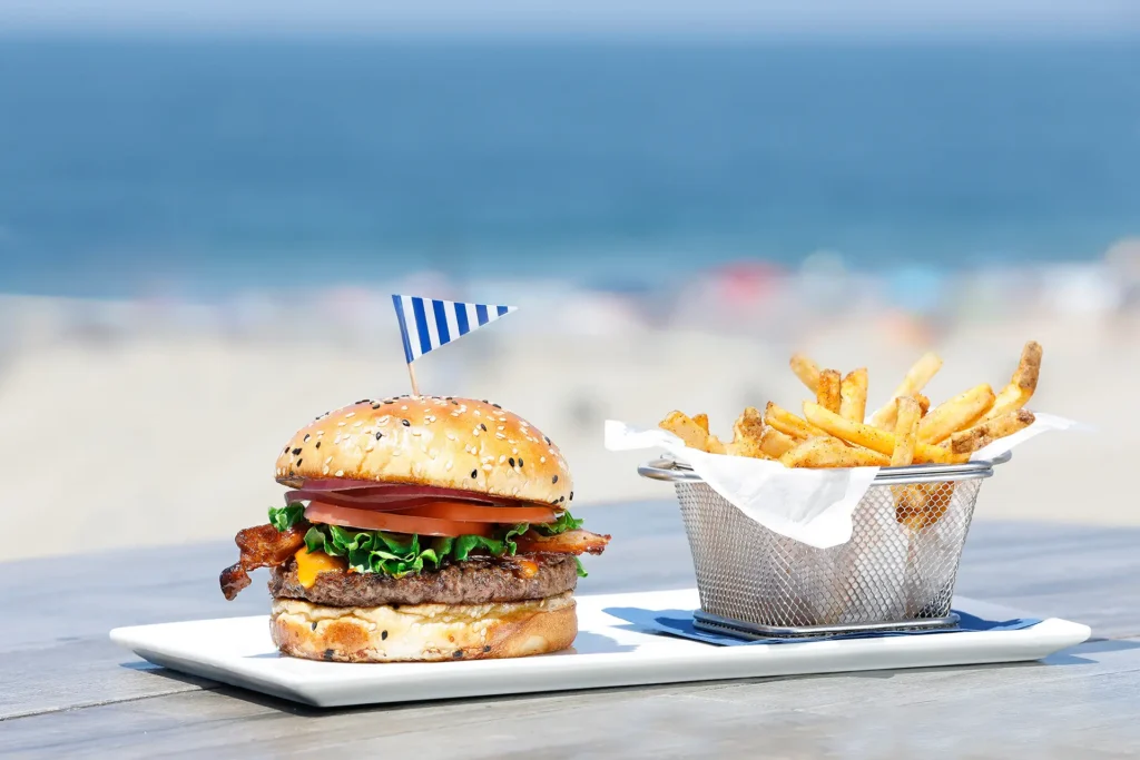 Cheeseburger with bacon, lettuce, tomato, and fries served on a plate by the beach at Seaside on the Pier.