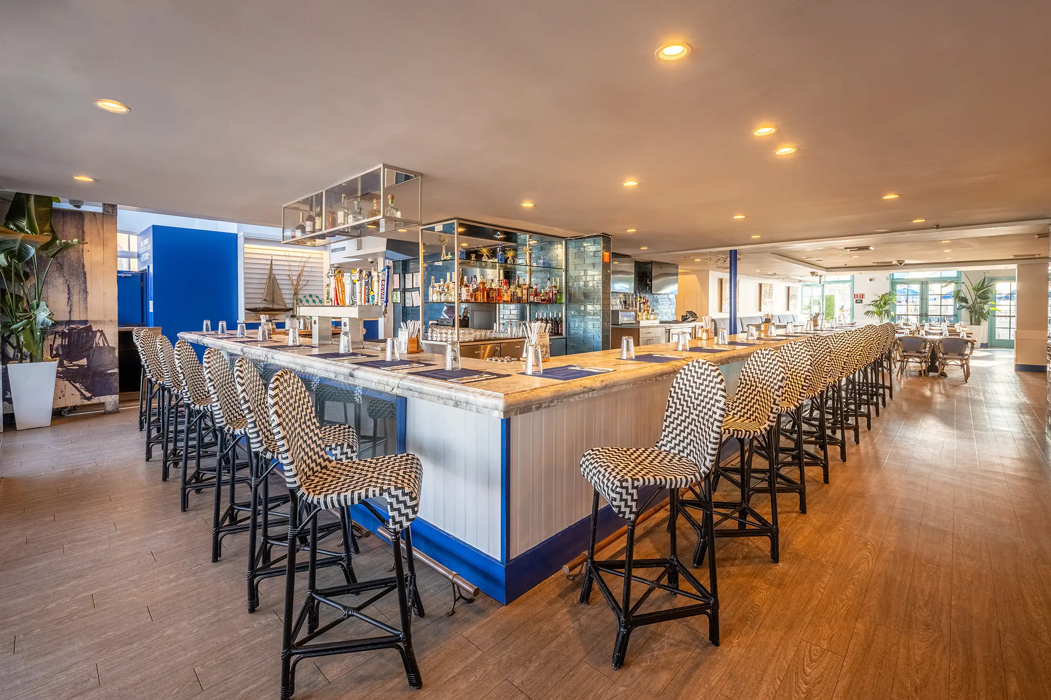 Bright coastal bar with wraparound seating and patterned stools at Seaside on the Pier.