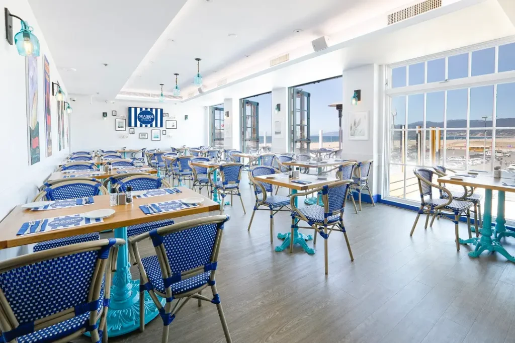 Sunlit upstairs dining area with ocean views through large windows at Seaside on the Pier.