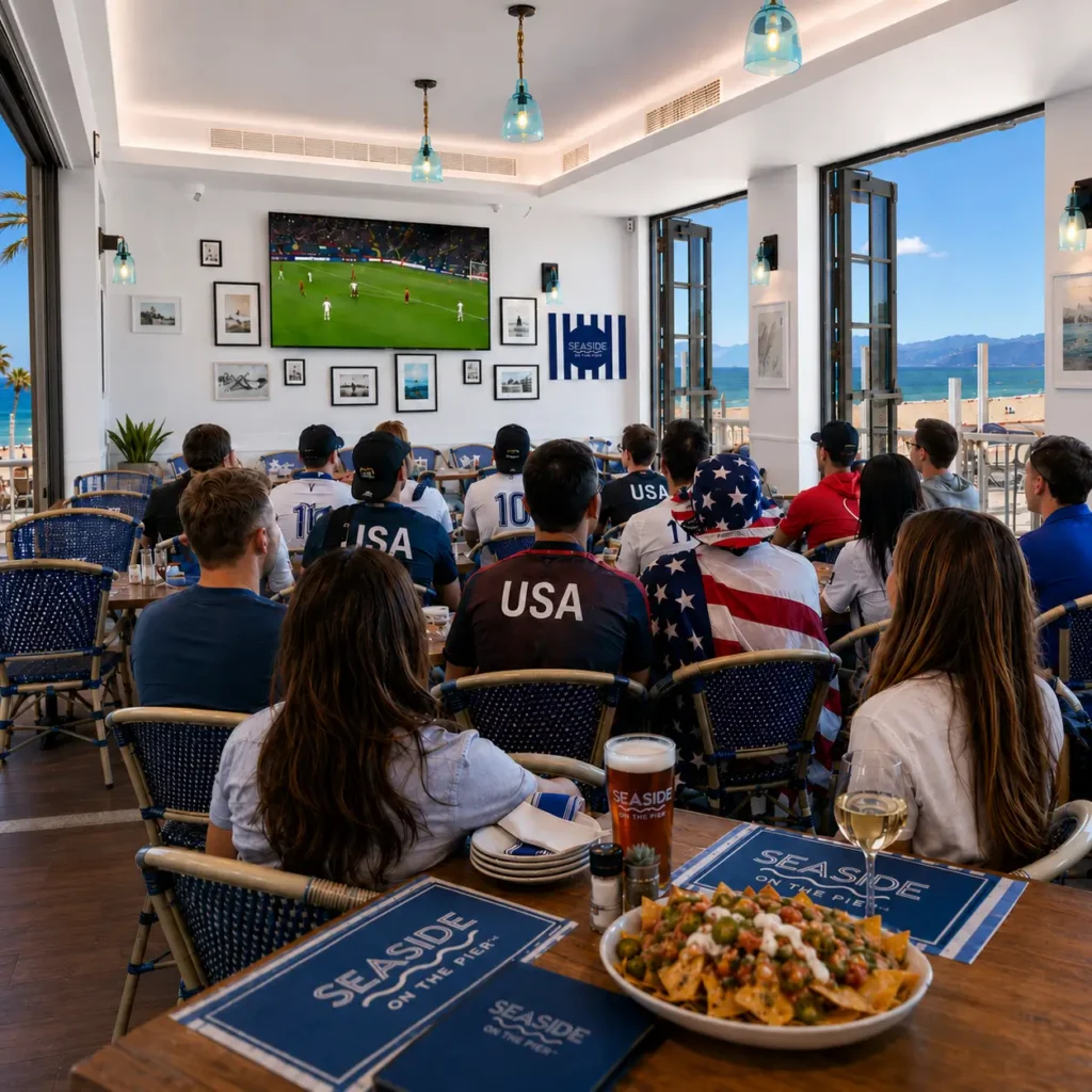 Fans watch soccer at Seaside on the Pier with beach views, food, and drinks.